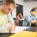Tiener die geconcentreerd schrijft tijdens een staatsexamen op het vso