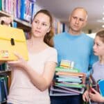 Ouders met tiener kiezen samen schoolspullen uit in de winkel
