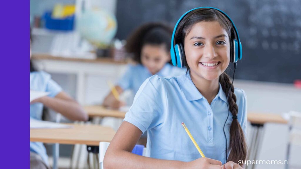 Lachend meisje met een koptelefoon tegen geluid in de klas, met een potlood in haar hand